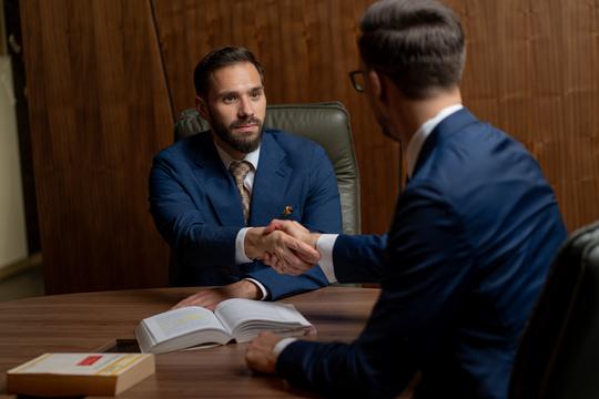 Mihnea Zamfirescu shaking hands with a client in a professional legal consultation, symbolizing trust, expertise, and business success.
