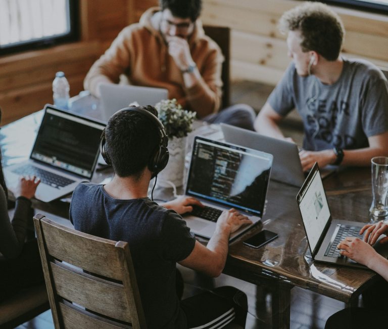 A group of young professionals working on laptops in a modern coworking space, symbolizing teamwork and startup innovation.